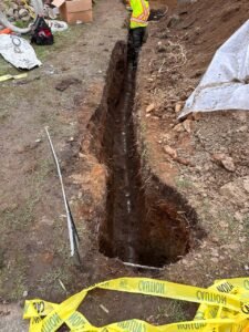 Drain tile trench excavation in a residential yard for perimeter drainage installation in Vancouver, BC.