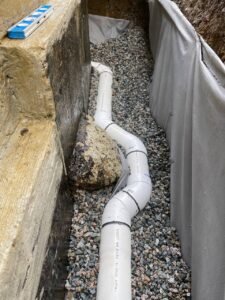 New PVC drain tile installed beside a residential foundation for perimeter drainage in Vancouver, BC.