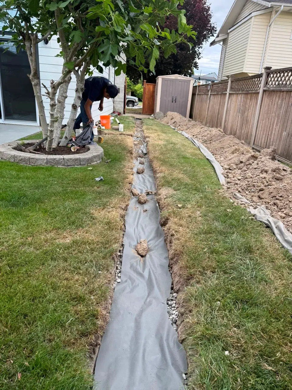 Residential French drain installation beside a home