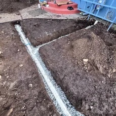 Cleaning a clogged perimeter drain to restore proper water flow around the foundation