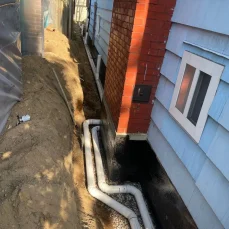Exterior foundation drainage system directing water away from the building