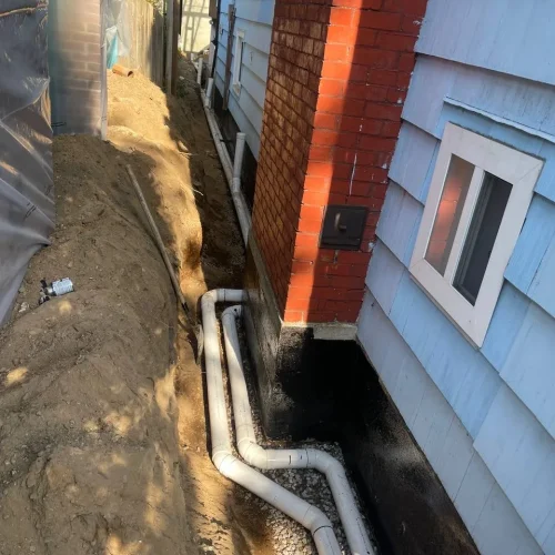 Exterior foundation drainage system directing water away from the building