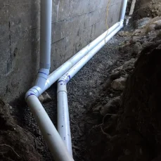 Perimeter drain excavation performed to access and replace underground drainage pipes